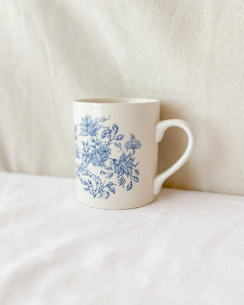 White mug with blue floral pattern on a white surface