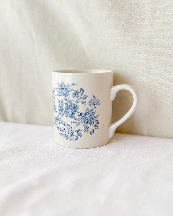 White mug with blue floral pattern on a white surface