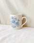 White mug with blue floral pattern on a white surface